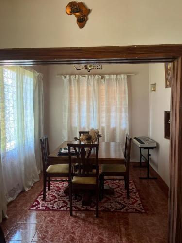 a dining room with a table and chairs and curtains at Kitonga Escape in Msaranga