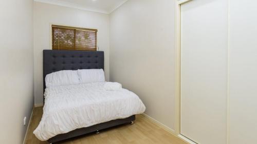 a bedroom with a bed with white sheets and a window at Bribie Beach View Retreat in Bellara