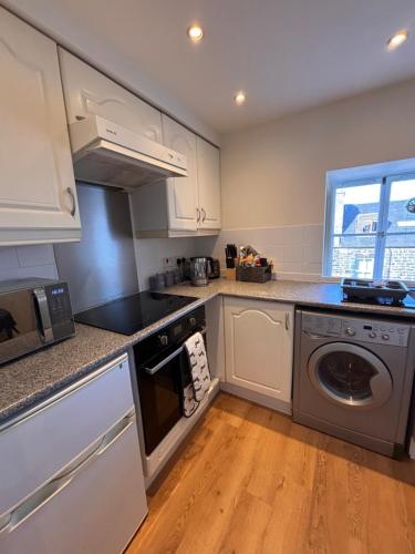 a kitchen with white cabinets and a washer and dryer at The Shore Modern Edinburgh 2 Bedroom Apartment in Edinburgh