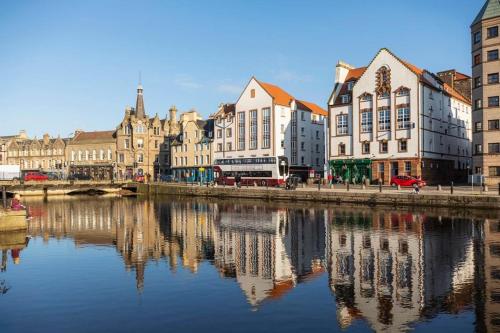 a group of buildings next to a river at The Shore Modern Edinburgh 2 Bedroom Apartment in Edinburgh