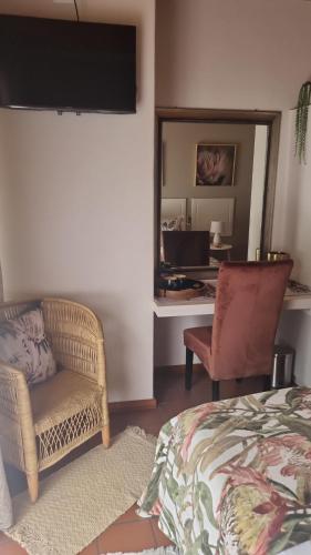 Un dormitorio con una cama, una silla y un espejo. en Boschendal Guesthouse, en Kimberley
