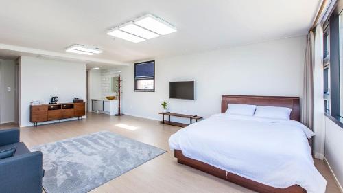 a bedroom with a bed and a tv and a couch at Here Now pension in Jeju
