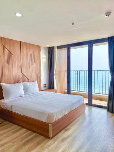 a bedroom with a bed with a view of the ocean at DA NANG BAY HOTEL in Danang