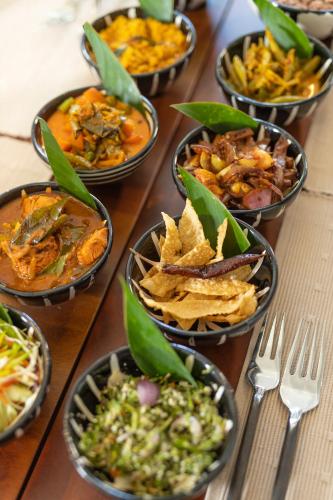 a table topped with bowls of different types of food at Clodagh Manor House by Seven Angels in Matale