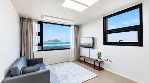 a living room with a couch and two windows at Here Now pension in Jeju