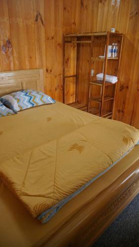 a bed in a room with a wooden wall at Vịnh Bốn Mùa - 4 Seasons Resort in Tân Phú