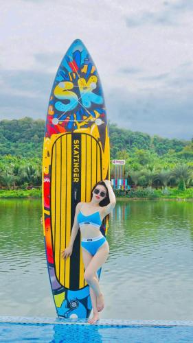 a woman standing next to a surfboard in the water at Vịnh Bốn Mùa - 4 Seasons Resort in Tân Phú