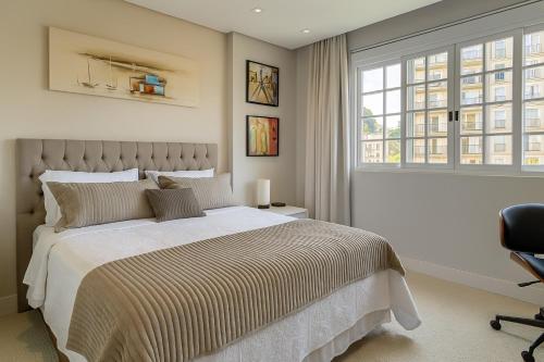 a bedroom with a bed and a chair and a window at Charmoso Flat na Serra - Granja Brasil Itaipava in Itaipava