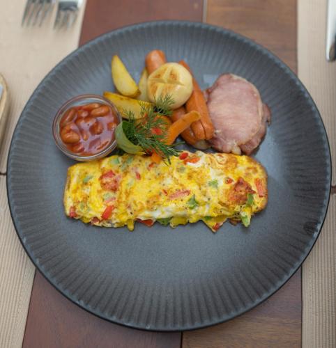 a plate of food with an omelet and meat and vegetables at Grand Bungalow Nuwara Eliya by Seven Angels in Nuwara Eliya