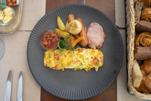 a plate of food with an omelet and meat and vegetables at Grand Bungalow Nuwara Eliya by Seven Angels in Nuwara Eliya