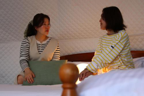 two women sitting on a bed looking at each other at 森の風 in Higashiizu