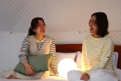 two women sitting on a bed talking to each other at 森の風 in Higashiizu