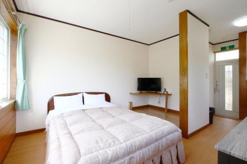 a bedroom with a large white bed and a television at 森の風 in Higashiizu