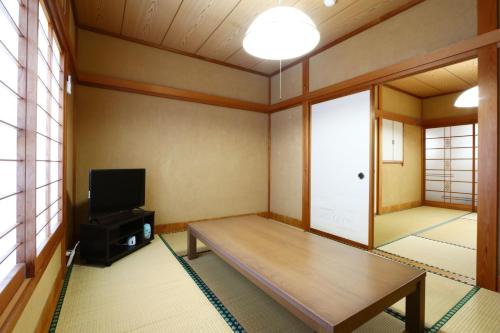 a room with a wooden table and a tv at 森の風 in Higashiizu