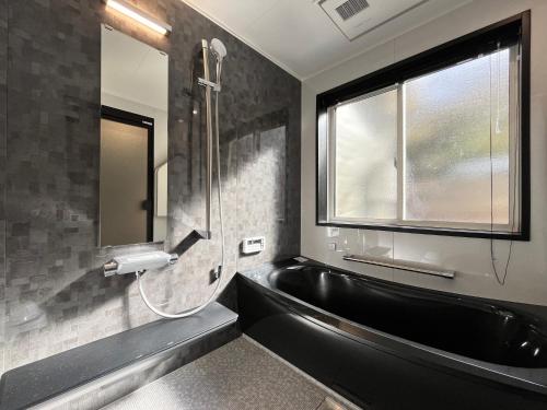 a bathroom with a black tub and a window at 森の風 in Higashiizu