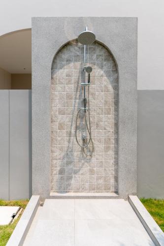a shower in a building with a stone wall at ภัทรา พูลวิลล่า ชะอำ Phattra Poolvilla Cha-am in Cha Am