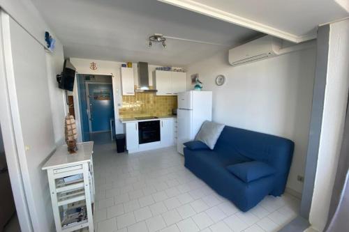 ein Wohnzimmer mit einer blauen Couch und einer Küche in der Unterkunft Softness of the shore on the port side in Frontignan