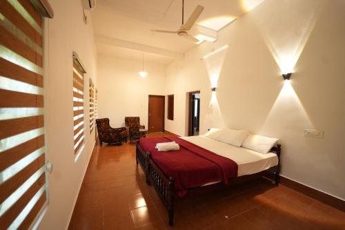 a bedroom with a bed with a red blanket at Chandralayam Heritage Homestay in Bekal