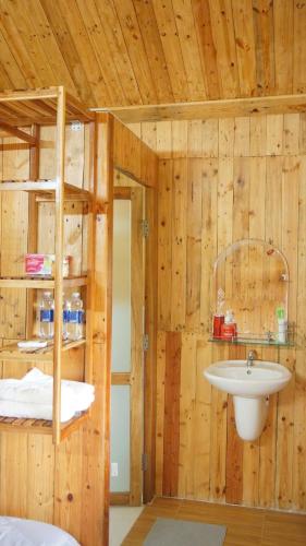 a bathroom with a sink in a wooden wall at Vịnh Bốn Mùa - 4 Seasons Resort in Tân Phú
