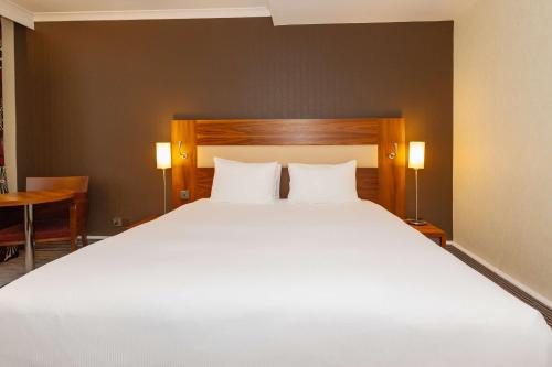 a bedroom with a large white bed with two pillows at Hilton London Olympia in London