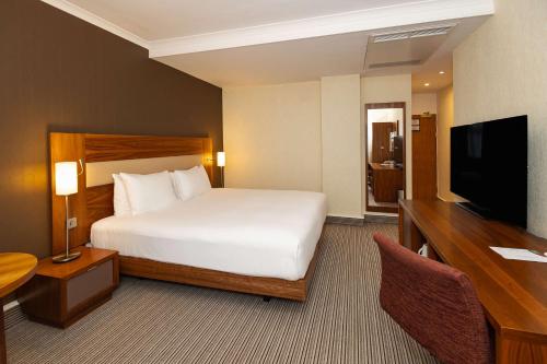 a bedroom with a bed and a desk and a television at Hilton London Olympia in London