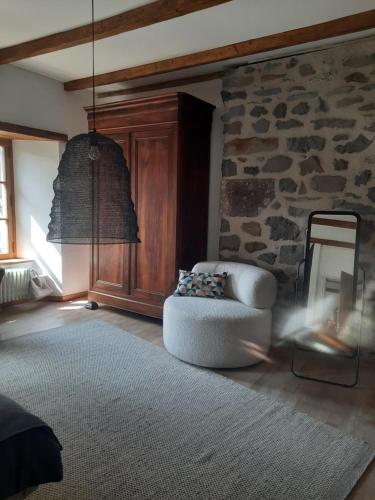 un salon avec une chaise et un mur en pierre dans l'établissement chambre d'hôtes Paulette et Pépin, à Graissac