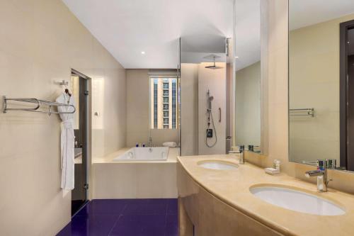 a bathroom with two sinks and a bath tub at V Hotel Dubai, Curio Collection by Hilton in Dubai