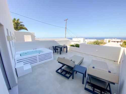 a balcony with tables and chairs and a hot tub at Nohēme Luxury Suites in Vourvoulos