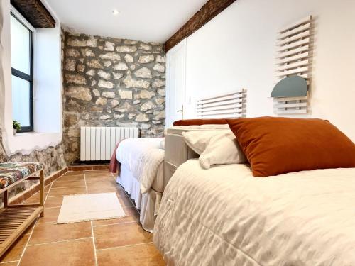 a bedroom with two beds and a stone wall at La Casuca de Orejo - Monabri in Orejo