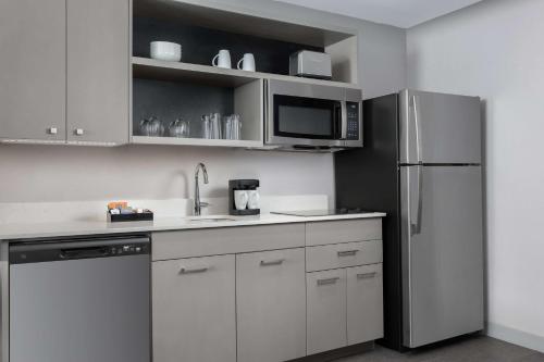 a kitchen with white cabinets and a stainless steel refrigerator at Homewood Suites By Hilton Newport Cincinnati in Newport