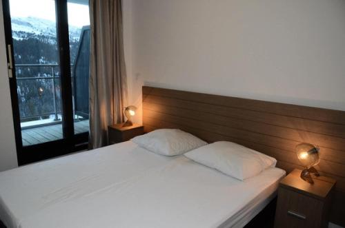 une chambre avec un grand lit blanc avec deux lampes dans l'établissement Résidence Les Terrasses De Veret - Appartement confortable · Au pied des pistes · Piscine · Spa · Parking inclus MAE-7391, à Flaine