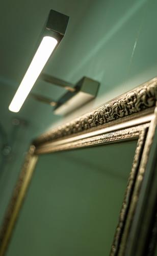 a mirror on a wall with a light and a ceiling at Chaika Gostinichny Kompleks in Karagandy