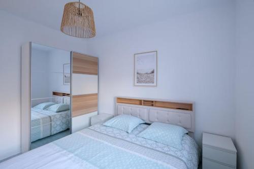 une chambre blanche avec un lit et un miroir dans l'établissement L'Ancre - Spacieux T4 élégant et lumineux vue mer, à La Baule