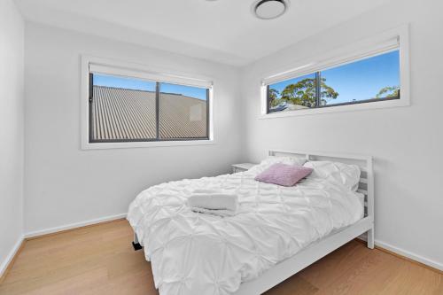 a white bedroom with a bed and two windows at luxury house near golf courses! Free wifi & Netflix in Gledswood Hills