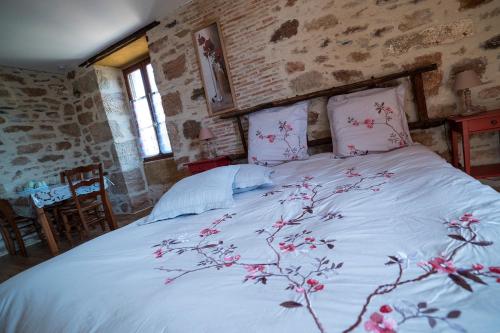 a bedroom with a white bed with red flowers on it at Ecuries de Saint Maurice- Maison d'hôtes de Gondou in Lacapelle-Marival