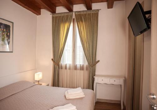 a bedroom with a bed and a window with a television at Agriturismo Vecio Portico in Marostica