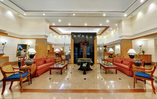 a lobby with red couches and tables in a building at The Fern-An Ecotel Hotel, Kochi in Cochin
