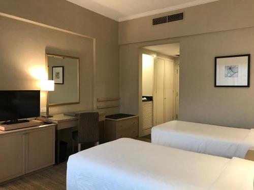 a hotel room with two beds and a desk and a television at York Hotel in Singapore