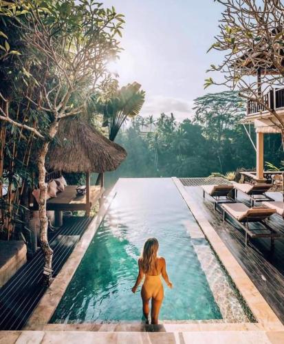 a woman walking in a pool at a resort at Villa Cella Bella Ubud in Ubud