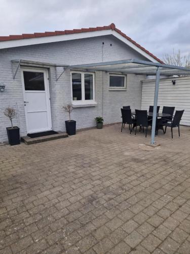 a patio with a table and chairs in front of a house at Rummeligt og stilfuldt hus nær Billund med 4 værelser og egen have in Grindsted