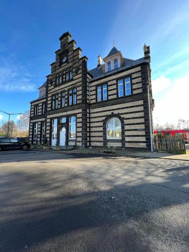 an old building with a clock tower on a street at Bahnhofsoase - Wellness & Spa am Krufter Bahnhof in Kruft