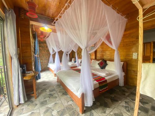 a bedroom with four beds with mosquito nets at House By The Stream in Lũng Tiềm