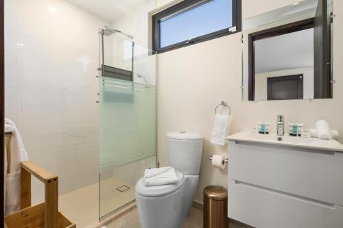 une salle de bain avec toilettes et douche en verre dans l'établissement 5 minutes walk to beach Palmbeach 623 by Bocobay, à Palm-Eagle Beach