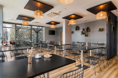 a restaurant with black tables and chairs and windows at Appart hôtel Q7 Lodge Lyon 7 in Lyon