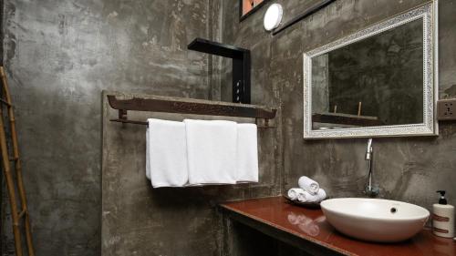 a bathroom with a sink and a mirror and towels at Pavillon Indochine Boutique - Hotel in Siem Reap
