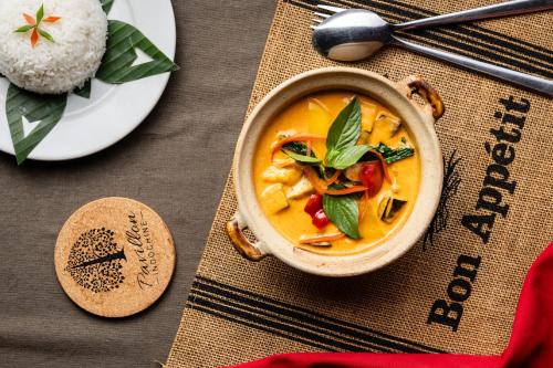 a bowl of soup on a table with a plate of food at Pavillon Indochine Boutique - Hotel in Siem Reap