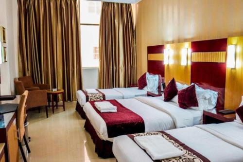 ein Hotelzimmer mit drei Betten und einem Schreibtisch in der Unterkunft Phoenix Hotel in Dubai