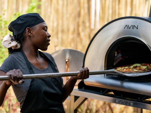 a woman is taking a pizza out of an oven at Amaya in Hoedspruit