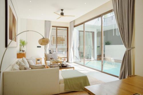 a living room with a white couch and a large window at Tree O'clock Pool Villa - Phuket in Thalang
