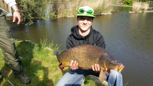 a man holding a large fish in a pond at Resort Svět in Úžice